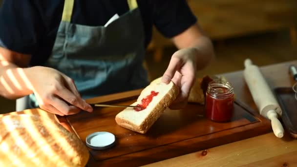 パンのスライスにイチゴジャムを広げる男 まな板にナイフで — ストック動画