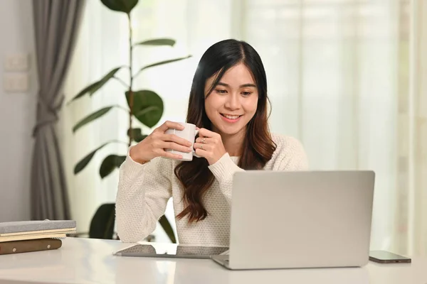 Atrakcyjna Młoda Azjatka Pijąca Kawę Oglądająca Film Lub Czytająca Maile — Zdjęcie stockowe