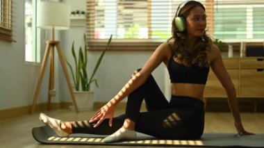 Genç ve çekici bir kadın yoga yapıyor. Oturma odasında balıkların efendisi pozisyonunda oturuyor. Yoga, meditasyon ve sağlıklı yaşam tarzı konsepti.