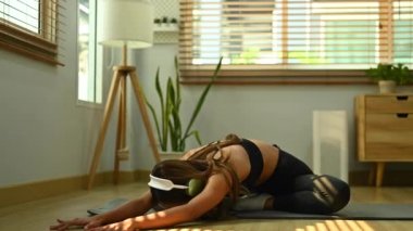 Spor giyim ve kulaklık giyen spor kadın oturma odasında vücut egzersizi yapıyor. Fitness, eğitim ve sağlıklı yaşam tarzı konsepti.