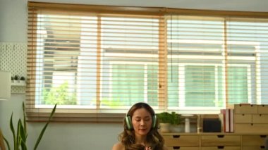 Huzurlu bir milenyum kadınının meditasyon yaparken, oturma odasında lotus pozisyonunda otururken..