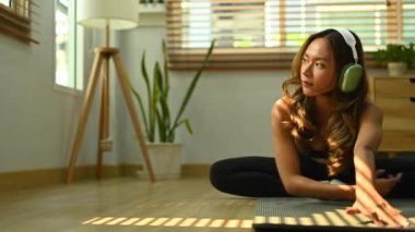 Evde yoga dersi vermeden önce vücudunu esneten genç bir kadın. Fitness, spor ve sağlıklı yaşam tarzı kavramı.