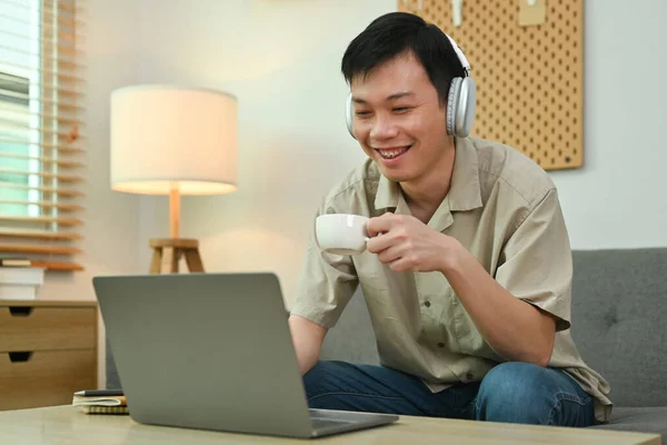 헤드폰을 착용하고 커피를 마시고 소파에서 노트북을 사용하는 즐거움을 — 스톡 사진