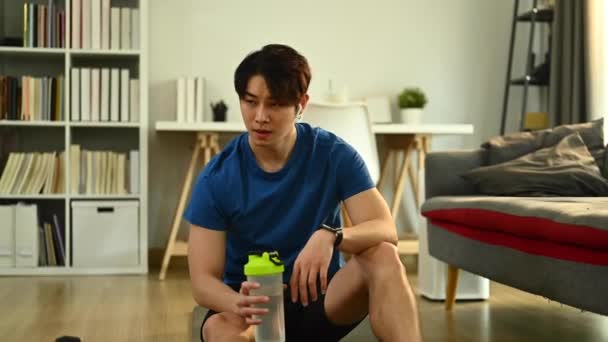 疲倦的健身者在家锻炼后 用塑料瓶擦干汗水和喝水 — 图库视频影像