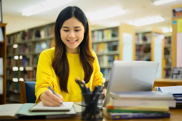 美しいアジアの大学の女性は レポートを準備し 図書館でノートパソコンで課題を行う — ストック写真