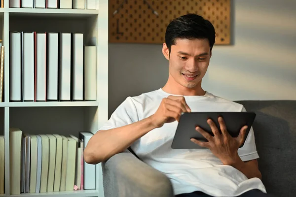 Kanepede Oturup Dijital Tablet Kullanan Sevimli Yetişkin Bir Asyalı Letişim — Stok fotoğraf