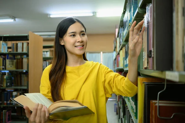 正の女子大生は 勉強のために棚に本を選択します 大学図書館での試験の準備 教育理念 — ストック写真