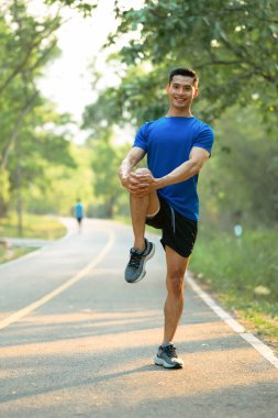 Spor kıyafetleri içinde erkek sporcu esneme egzersizi yapıyor, sabah antrenmanına hazırlanıyor..