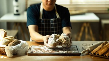 Erkek fırıncı elleri ön planda çeşitli ekmek ve hamur çeşitleriyle taze fırınlanmış..