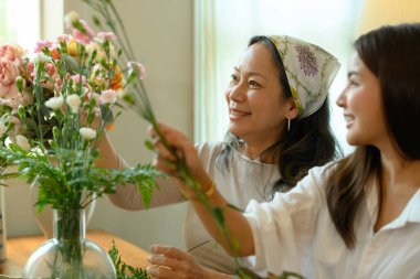 Son sınıf öğrencisi kadın ve yetişkin kızın oturma odasında güzel bir buket oluşturması. Aile ve eğlence etkinliği konsepti.