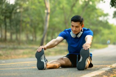 Atletik adam sabah koşmadan önce kaslarını esnetiyor. Fitness, spor ve sağlıklı yaşam tarzı kavramı.