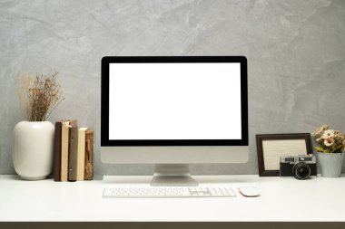Boş ekran bilgisayarı, resim çerçevesi ve kitapları olan şık bir iş yeri. Montaj için boş ekran Grafik ekranınız.