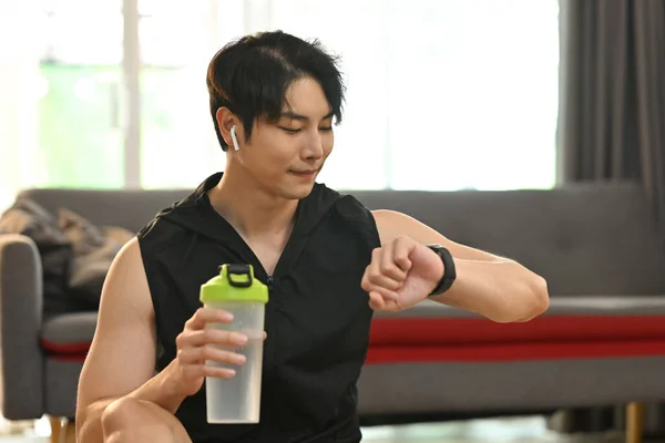 stock image Athletic man checking his heart rate data on smartwatch during morning workout at home. Healthy lifestyle concept.