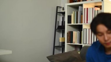 Günlük giysiler içinde yakışıklı Asyalı bir adam kredi kartı tutuyor ve iinternet ya da internet üzerinden ödeme yapmak için akıllı telefon kullanıyor..