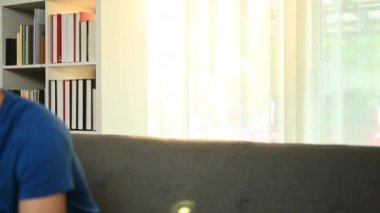 Tatmin olmuş Asyalı adam kredi kartı tutuyor ve cep telefonu kullanıyor, online işlemler yapıyor, evden online alışveriş yapıyor.. 