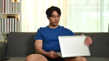 Gülümseyen Asyalı erkek serbest çalışan eller dizüstü bilgisayarın kapağını açıyor ve klavyede yazıyor. Serbest çalışma, uzaktan çalışma ve teknoloji.