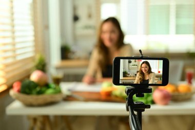 Genç kadın vlogger akıllı telefondan sağlıklı yiyecekler hakkında video içeriği kaydediyor, seçici odaklanma.