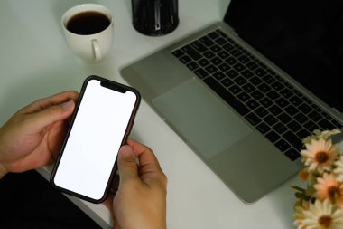 Ofis masasında dizüstü bilgisayarlı ve akıllı telefon kullanan bir adamın yakın görüntüsü. Reklam mesajınızı boş ekran.