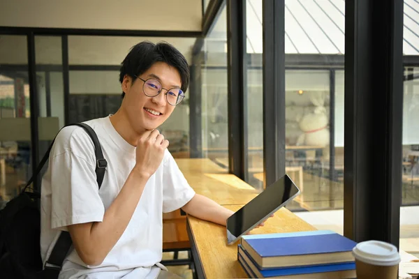 コーヒーショップに座ってタブレットを使用してメガネでアジアの男学生の肖像画 技術の概念 — ストック写真
