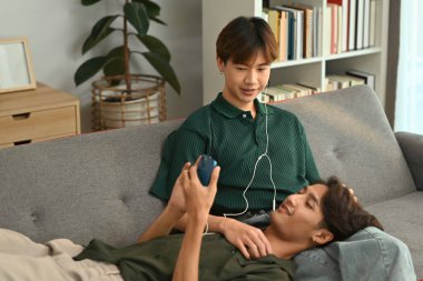 Romantik genç eşcinsel çift arka planda gökkuşağı bayrağıyla akıllı telefonlarıyla selfie çekiyor. LGBT ve aşk konsepti.