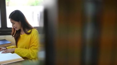 Huzurlu üniversite öğrencisi kütüphanede oturmuş ders kitabı okuyor. Eğitim, öğrenme ve bilgi kavramı.