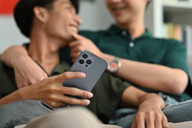 Akıllı telefon tutan ve erkek arkadaşıyla konuşan bir adamın yakın plan fotoğrafı. LGBT, aşk ve yaşam tarzı ilişki kavramı.