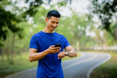 Tatmin olmuş erkek sporcu akıllı telefon uygulamasında eğitim programını kontrol ediyor. Teknoloji sağlığı, sağlık konsepti.