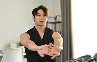 Evde spor yapmadan önce esneme hareketleri yapan aktif bir erkek sporcu. Sağlıklı yaşam tarzı kavramı.