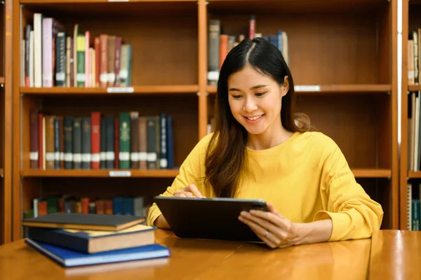 有兴趣的亚裔女学生使用数码平板电脑 在图书馆做课堂教学 学习和人的概念 — 图库照片