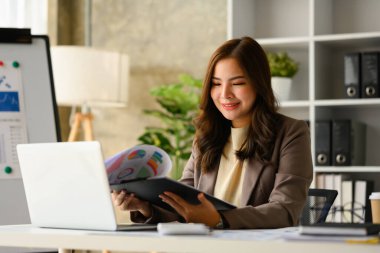 Lüks takım elbiseli muhteşem bayan girişimci modern işyerinde satış pazarlama projesi üzerinde çalışıyor..