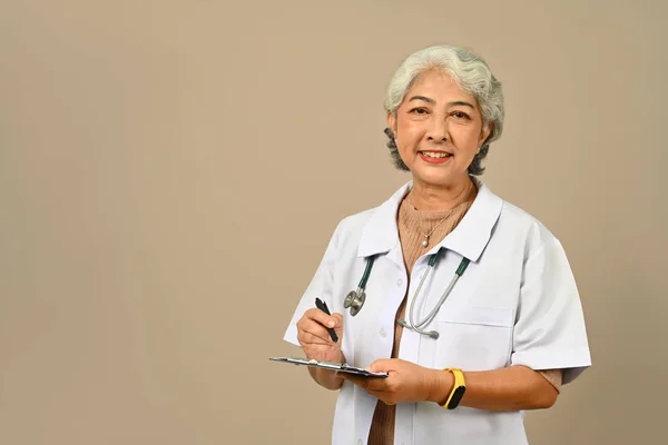 自信成熟的医生 总体上身穿白色的医疗服 听诊器站在米黄色的背景上 保健概念 — 图库照片