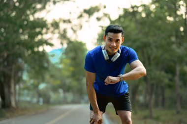 Yorgun erkek sporcu antrenman sonuçlarını izlemek için ara veriyor. Sağlıklı yaşam tarzı kavramı.