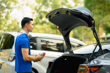 Spor kıyafetli bir adam spor salonuna giderken arabasının yanında duruyor. Fitness yaşam tarzı konsepti.