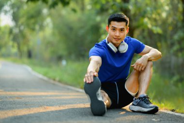 Parktaki antrenmandan önce esneme hareketleri yapan motive bir sporcu. Fitness, spor ve sağlıklı yaşam tarzı kavramı.