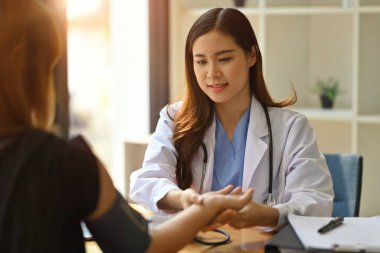 Beyaz üniformalı kadın doktor hasta nabzını parmaklarıyla kontrol ediyor. Sağlık ve Tıp Konsepti.