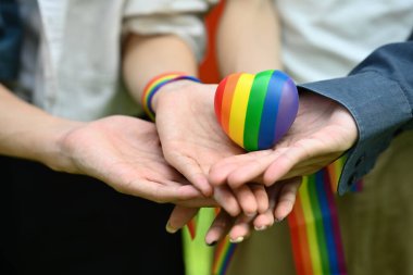 Gökkuşağı farkındalığı bilekliği takan bir grup genç ellerinde gökkuşağı kalbiyle eşcinsel gururunu kutluyor. LGBT topluluk kavramı.