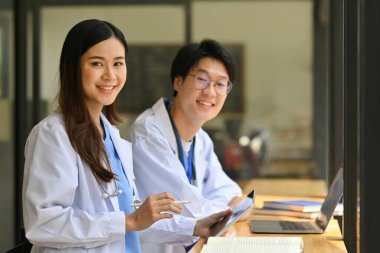 Beyaz üniformalı, dijital tablet kullanan kadın ve erkek doktor modern hastanedeki hasta teşhisini tartışıyor..