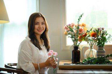 Çiçekçide çiçek buketi yapan genç ve güzel bir çiçekçi. Küçük işletme kavramı.