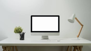 Boş ekran bilgisayar, lamba, kalem tutacağı ve saksı bitkisi beyaz masada. Web sayfan için boş ekran ya da metni tanıt. 