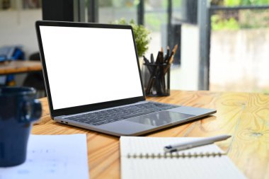 Dizüstü bilgisayarı, not defteri ve bir fincan kahvesi olan ahşap ofis masası. Reklam metniniz için beyaz boş ekran.