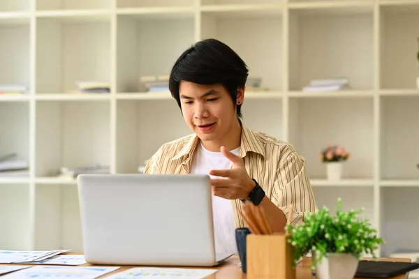Yakışıklı Asyalı Girişimci Video Görüşmesinde Konuşuyor Müşteriye Yerindeki Dizüstü Bilgisayarla — Stok fotoğraf