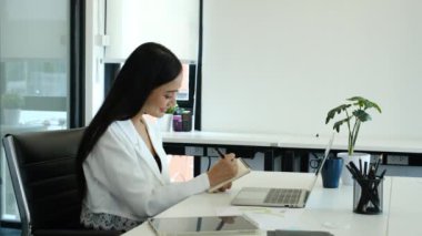 İş kadını önemli notlar yazıyor, çalışma masasındaki çalışma programını kontrol ediyor..