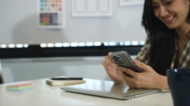 Akıllı telefon kullanan, sosyal medyayı izleyen, iş yerinde arkadaşlarıyla sohbet eden hoş bir iş kadını..