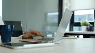 Kadın yöneticinin elleri dizüstü bilgisayarda yazarken, e-postaları kontrol ederken ya da ofis masasında internette sörf yaparken yan görünüm.