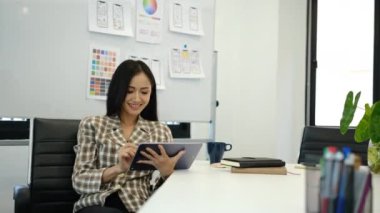 Tablet kullanan güzel kadın tasarımcı, modern işyerinde mobil uygulama geliştirme üzerinde çalışıyor.