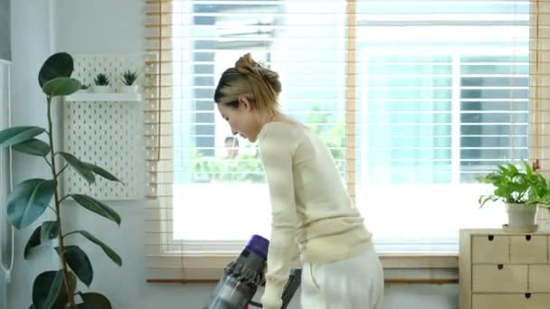 居間の掃除機で掃除機で床を掃除しているカジュアルな服の若い女性 テクノロジーの概念 — ストック動画