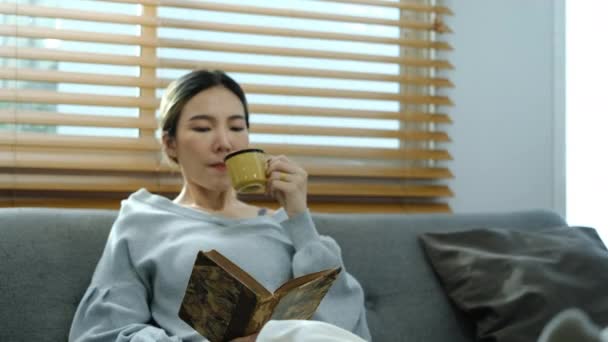 Приємна Азіатська Жінка Має Ранкову Каву Читає Книгу Зручному Дивані — стокове відео