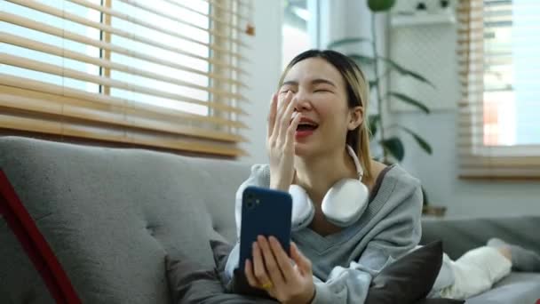 亚洲女人躺在沙发上 用智能手机给她的朋友打一个视频电话 在线通信概念 — 图库视频影像
