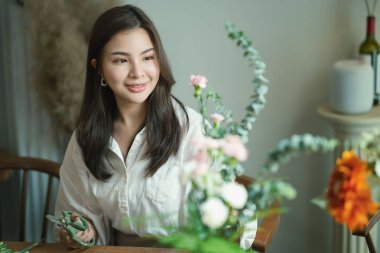 Güzel genç bayan küçük işletme sahibi çiçekçi dükkanında bir buket pembe çiçek hazırlıyor..