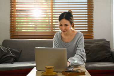 İnternette çalışan çekici genç bir kadın, evde dizüstü bilgisayardan alışveriş yapıyor. İnsanlar, teknoloji ve yaşam tarzı.